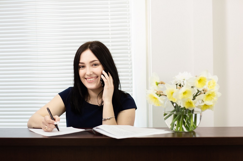 Beautiful girl at the reception desk answering the call in dental office
