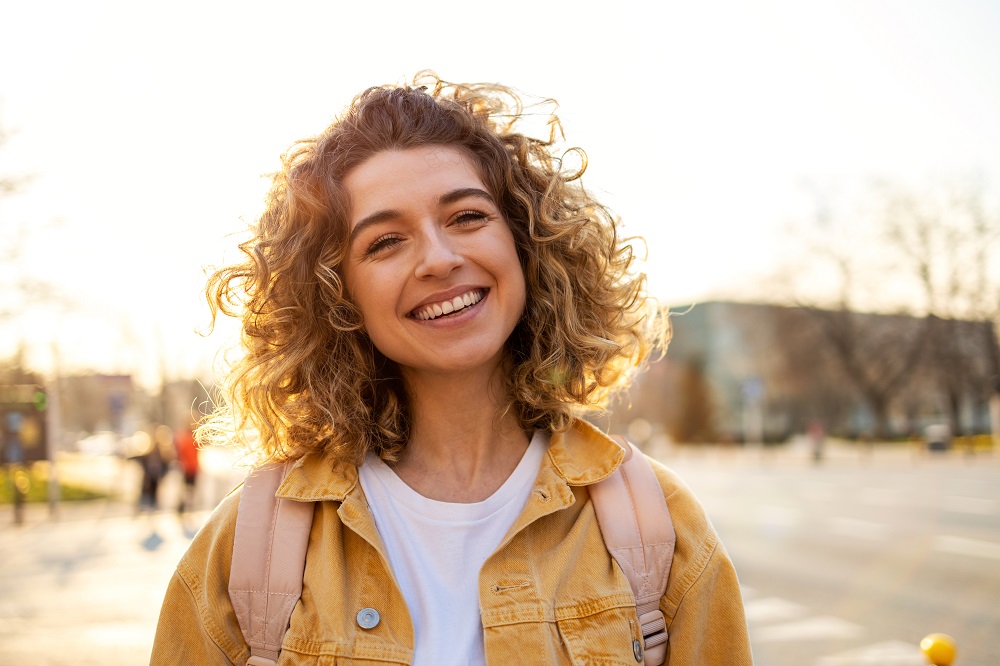 Woman smiling on a street in the sunshine outdoors