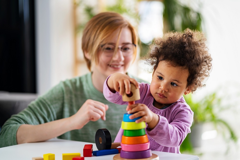 Mother looking at a child playing with an educational didactic t