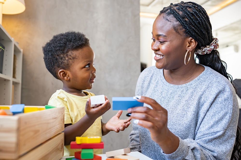 Mother smiles at her son while playing with toy blocks